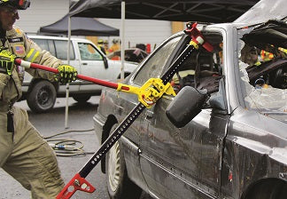 A fireman is using the First Responder Jack to widen the window area of a car.